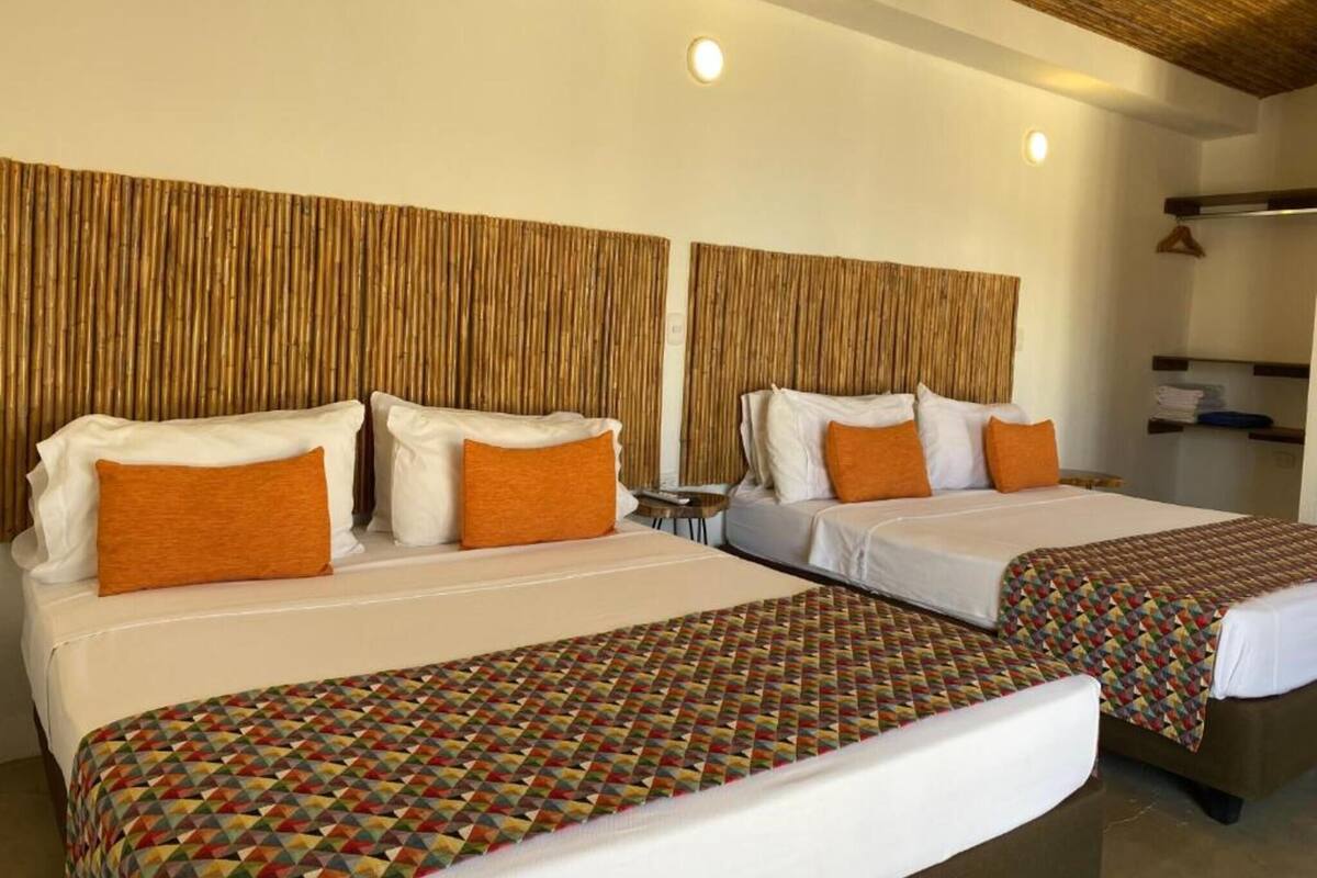 Two single beds with patterned bedspreads, a bamboo headboard, and a small table between them.