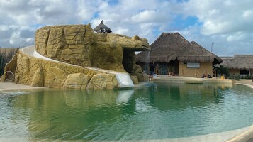 Una piscina al aire libre, sombrillas, sillones reclinables de piscina