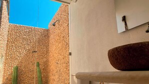 A bathroom with a stone wall, a large sink, and a cactus. - Hotel Wayira Beach by On vacation (Manaure)