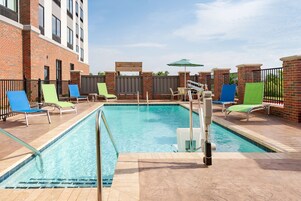 Una piscina al aire libre, sillones reclinables de piscina