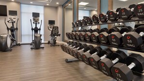 Un gimnasio con varios equipos de ejercicio, como cintas de correr, bicicletas estáticas y mancuernas.