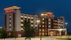 Un hotel Hampton Inn & Suites con un diseño moderno, que cuenta con un estacionamiento amplio y una entrada bien iluminada.