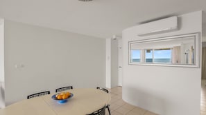 A dining area with a round table, chairs, and a bowl of fruit.