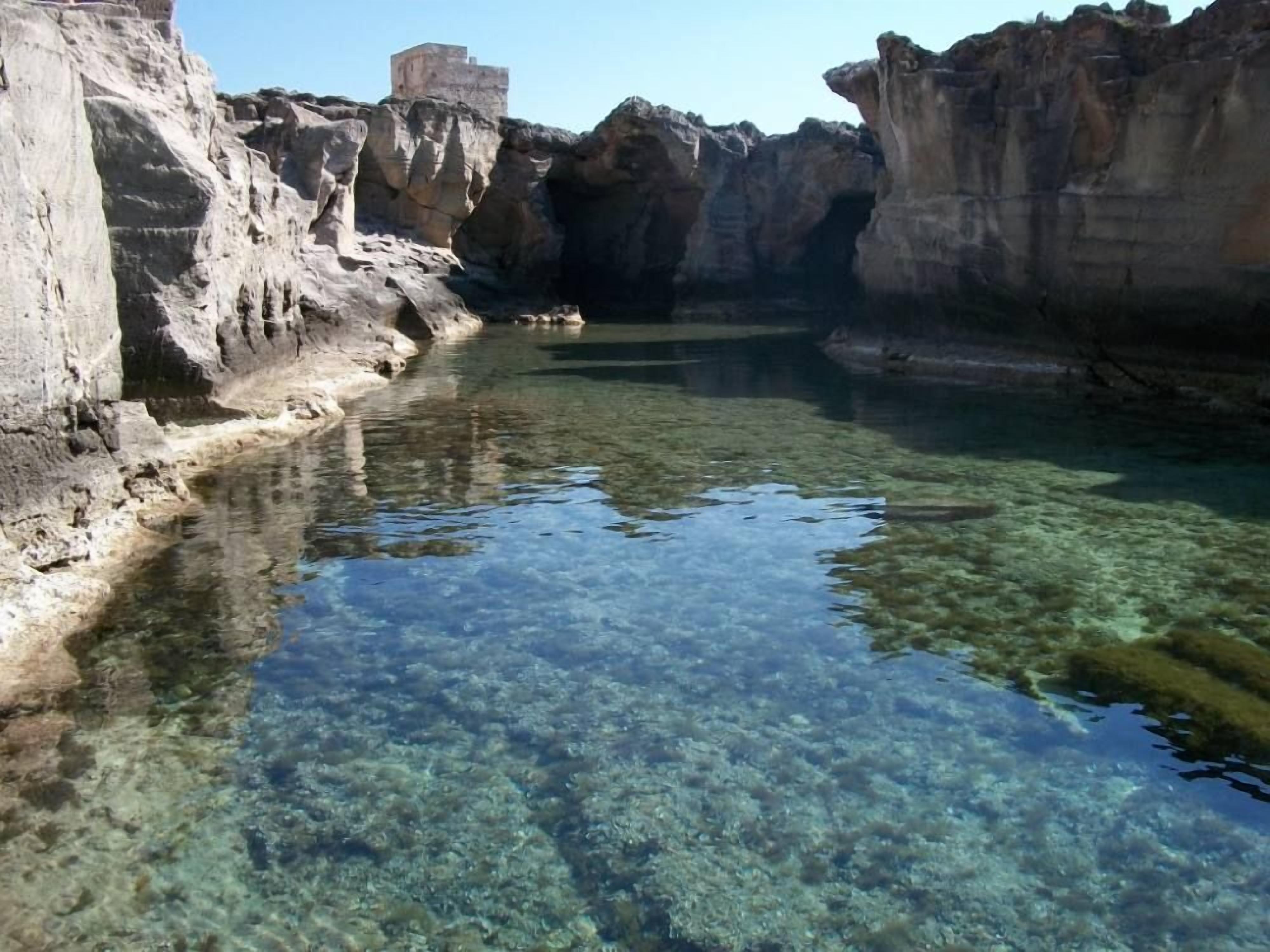 Une étendue d’eau claire, bordée de falaises rocheuses.