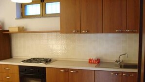 Una cocina con armarios de madera, estufa a gas, lavavajillas y una ventana sobre el fregadero.