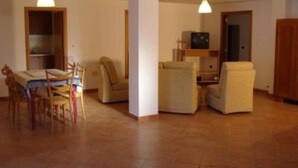 Amplia sala de estar con una mesa de comedor, dos sillones, un sofá y un televisor.