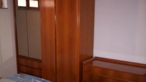 Un dormitorio con cama, armario de madera y cómoda.