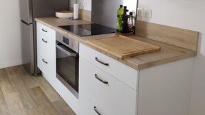 Eine moderne Küche mit weißen Schränken, einem Edelstahlkühlschrank, einem eingebauten Backofen und einer Holzausziehtafel.