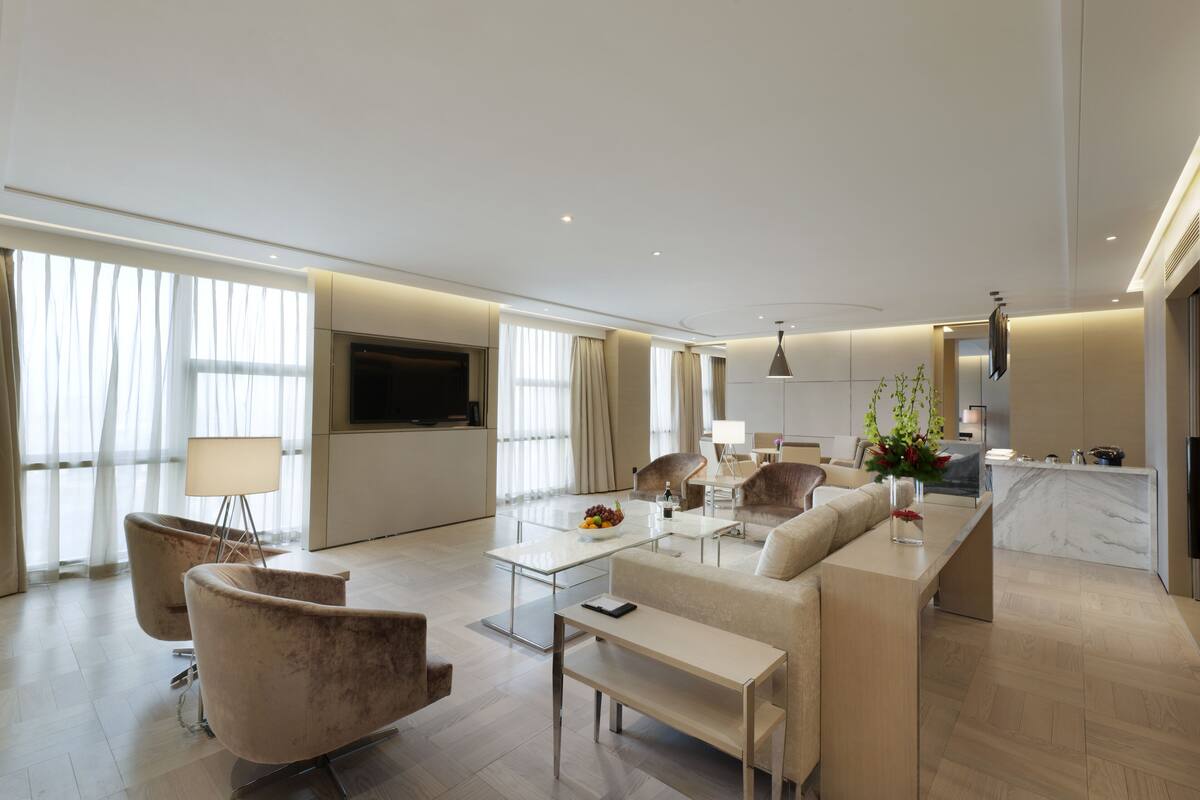 A modern living room with a sofa, armchairs, a coffee table, and a TV.