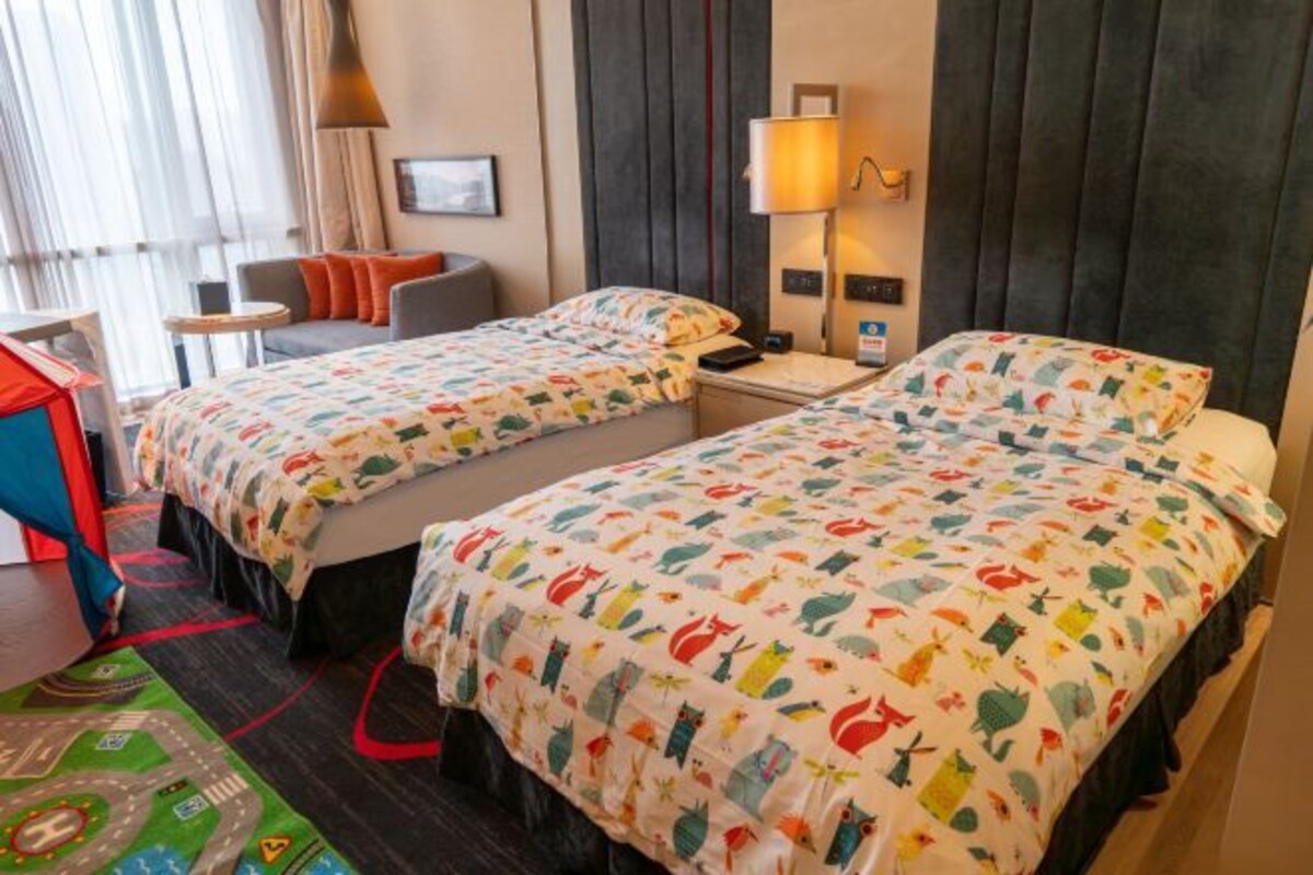A hotel room with two beds, a sofa, a small table, and a lamp.