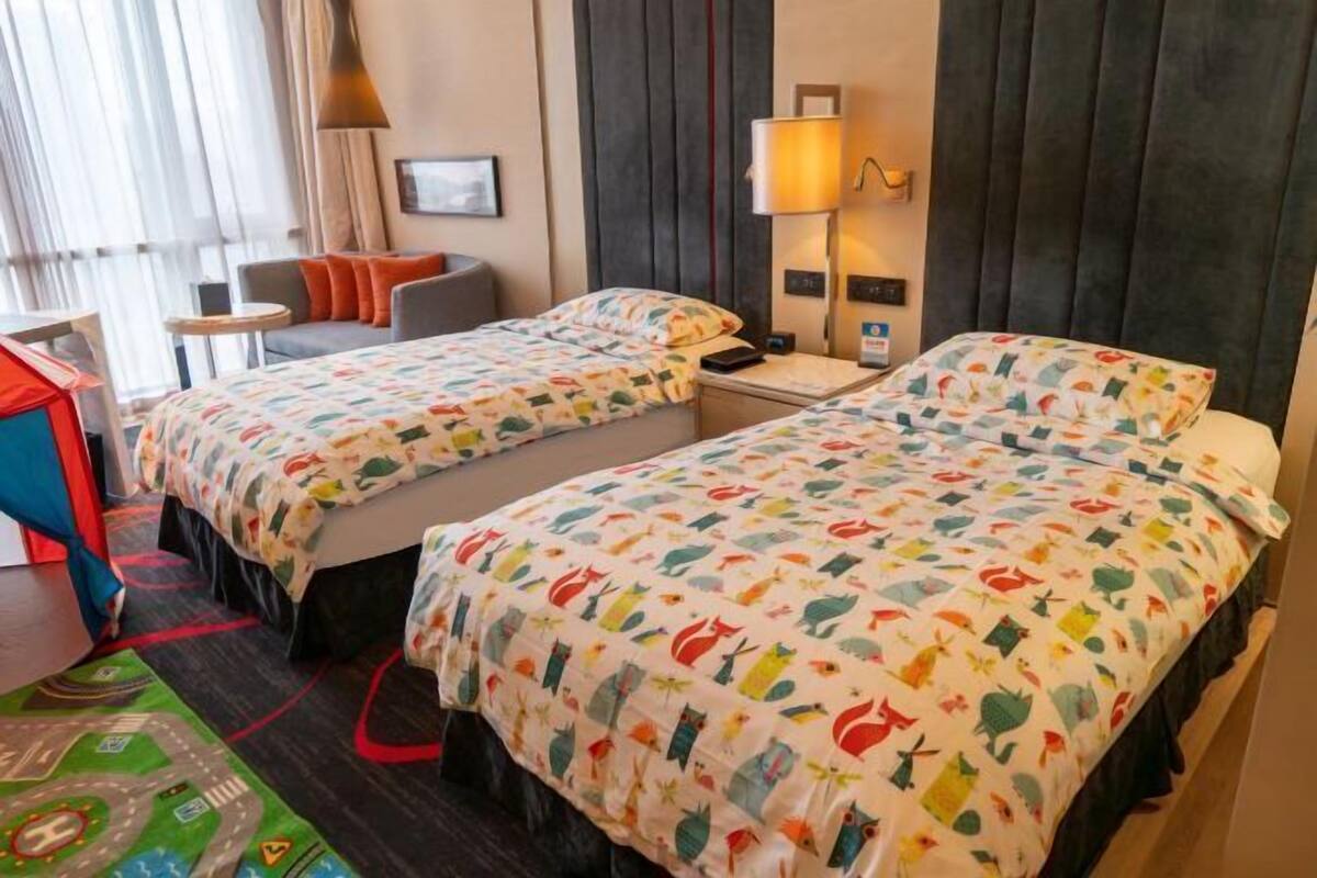 A hotel room with two beds, a sofa, a small table, and a lamp.