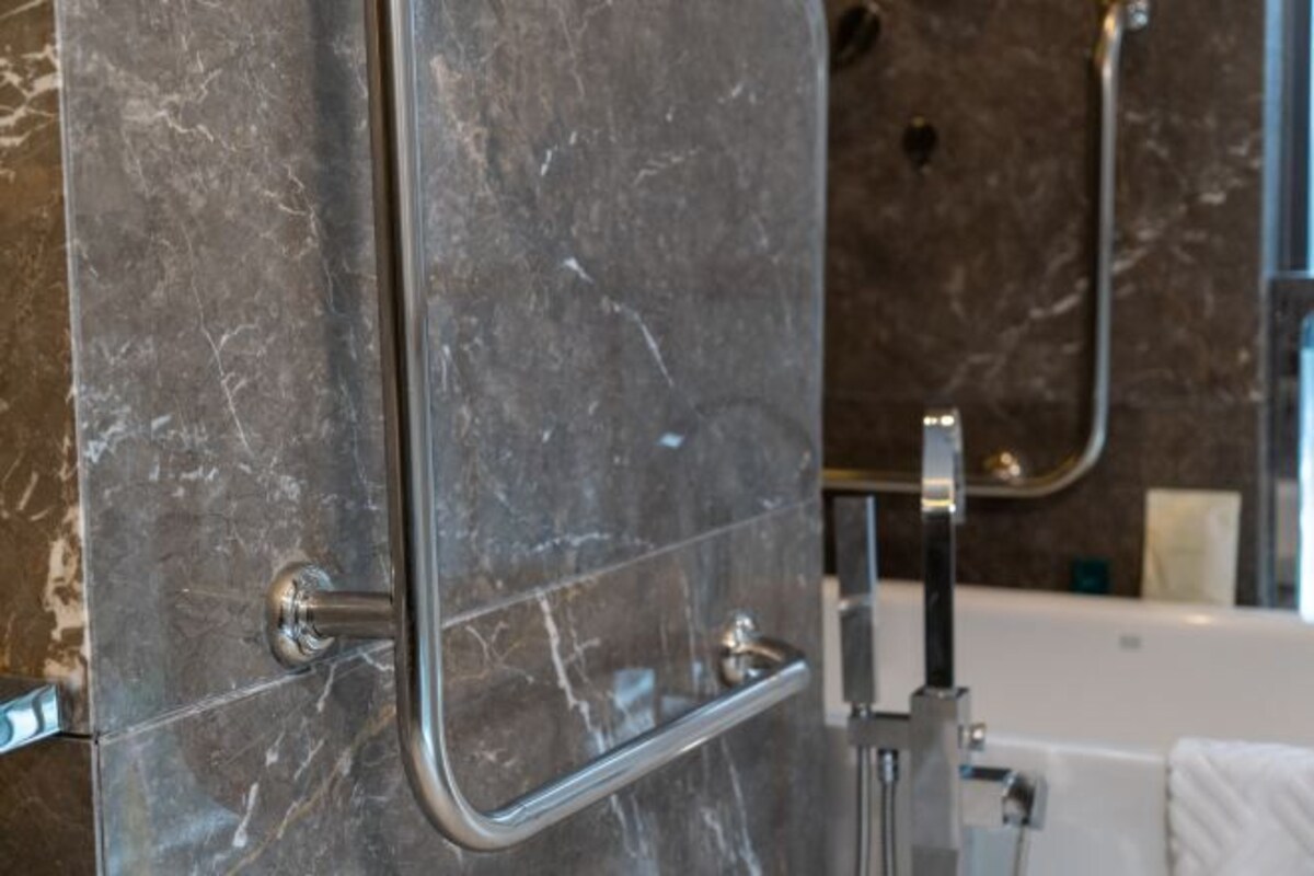 A bathroom with a marble wall, a bathtub, and a shower area.
