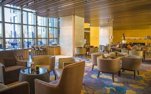 A hotel lobby with a seating area, a reception desk, and large windows. - Hilton Xi'an High-tech Zone (Xi'an)