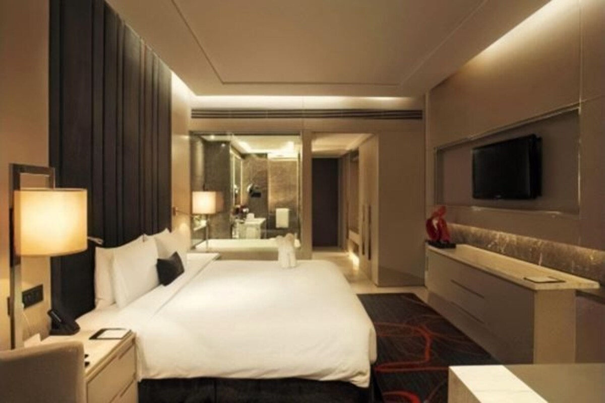 A hotel room with a large bed, bedside tables, a TV mounted on the wall, and a mirror.
