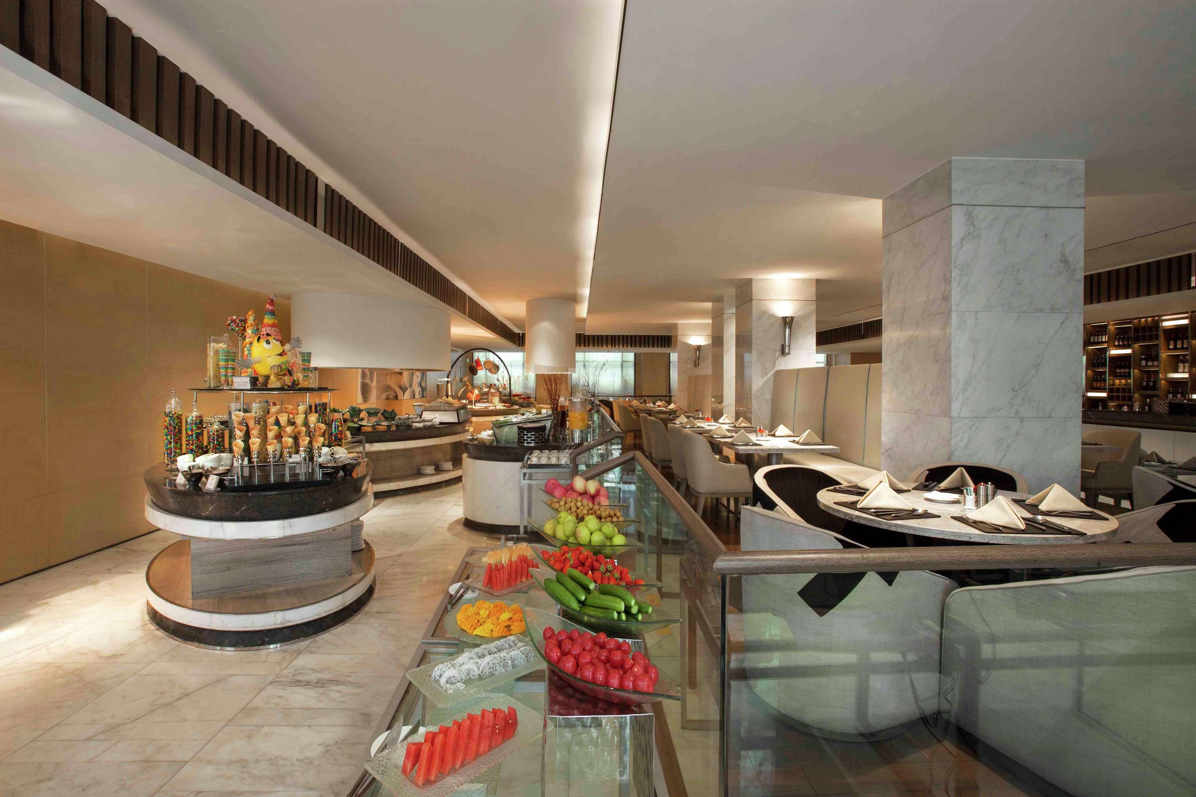 A buffet area with various food items and a seating area with tables and chairs.