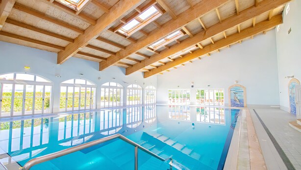 An indoor swimming pool with skylights, large windows, and a view of the outdoors. - Townhouse pool and jacuzzi in Portimão (Portimão)