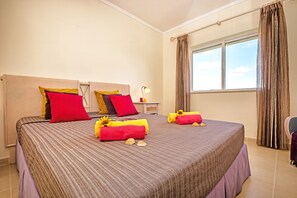 A hotel room with a large bed, a nightstand, a lamp, and a window with curtains.