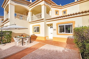 A multi-story building with balconies, a patio area with a table and chairs, and a door marked 'RESERVES'. - Townhouse pool and jacuzzi in Portimão (Portimão)
