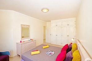 A bedroom with a bed, dresser, mirror, wardrobe, and a ceiling light. - Townhouse pool and jacuzzi in Portimão (Portimão)