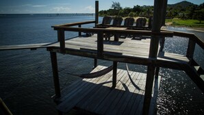 Um deck de madeira com cadeiras e uma mesa, com vista para a água.