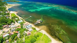 Vista aérea de uma área costeira com casas, uma praia e águas azuis cristalinas.