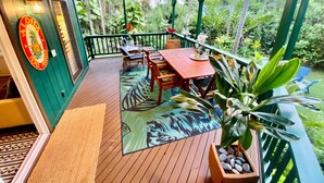 A wooden deck with a table and chairs, surrounded by lush greenery.
