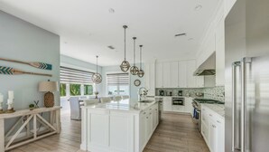 Una cocina amplia con armarios blancos, una isla grande y un refrigerador de acero inoxidable.