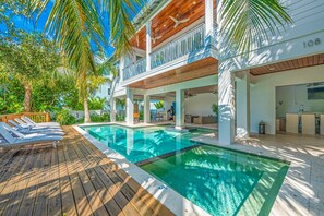 Ein Poolbereich mit Holzterrasse, Liegestühlen und einem klaren, blauen Pool.