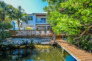 Un hotel moderno con piscina, terraza de madera y exuberante vegetación.