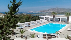 A pool area with lounge chairs and a view of the sea and cityscape. - One bed, fully detached apartment, 1 bath, sea view, communal pool, breakfast (Naxos)