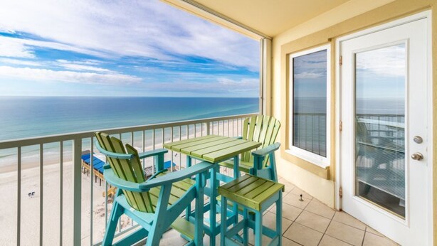 A balcony with a view of the ocean, featuring a table and chairs. - Boardwalk   983 (Gulf Shores)