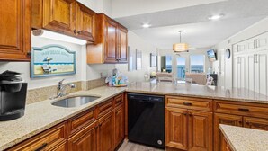 A kitchen with wooden cabinets, a built-in dishwasher, a coffee maker, and a sign that reads "Our Beach House". - Boardwalk   983 (Gulf Shores)