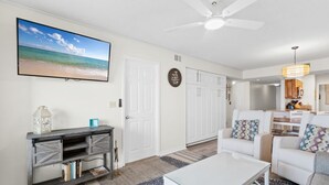 A living room with a television, white sofas, a coffee table, and a ceiling fan. - Boardwalk   983 (Gulf Shores)