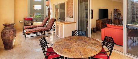 A dining area with a round table and chairs, a sofa, and a TV.