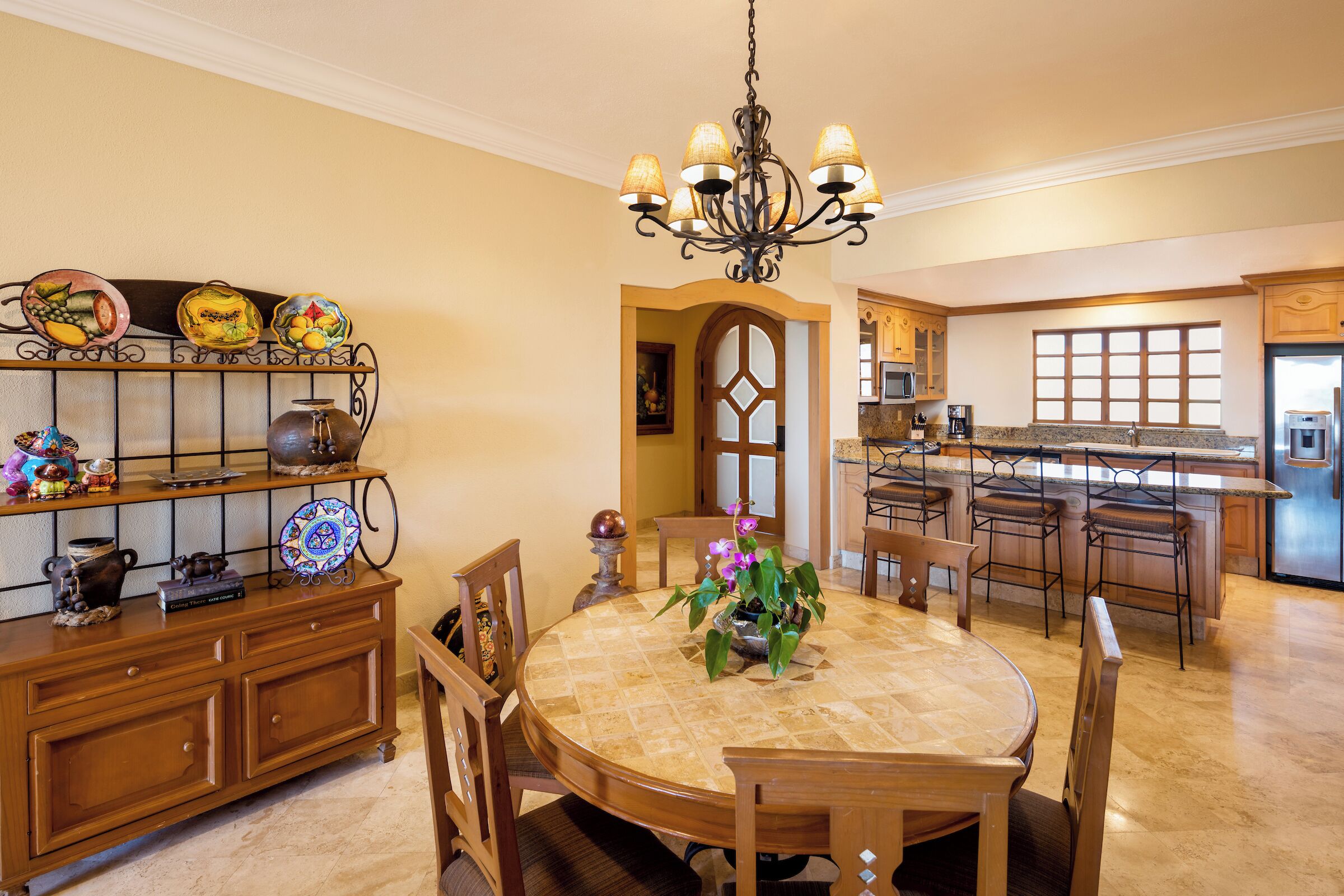 Una cocina amplia con una isla central, muebles de madera y un comedor con mesa y sillas redondas.