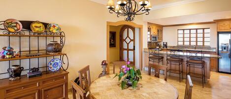 Una cocina amplia con una isla central, muebles de madera y un comedor con mesa y sillas redondas.