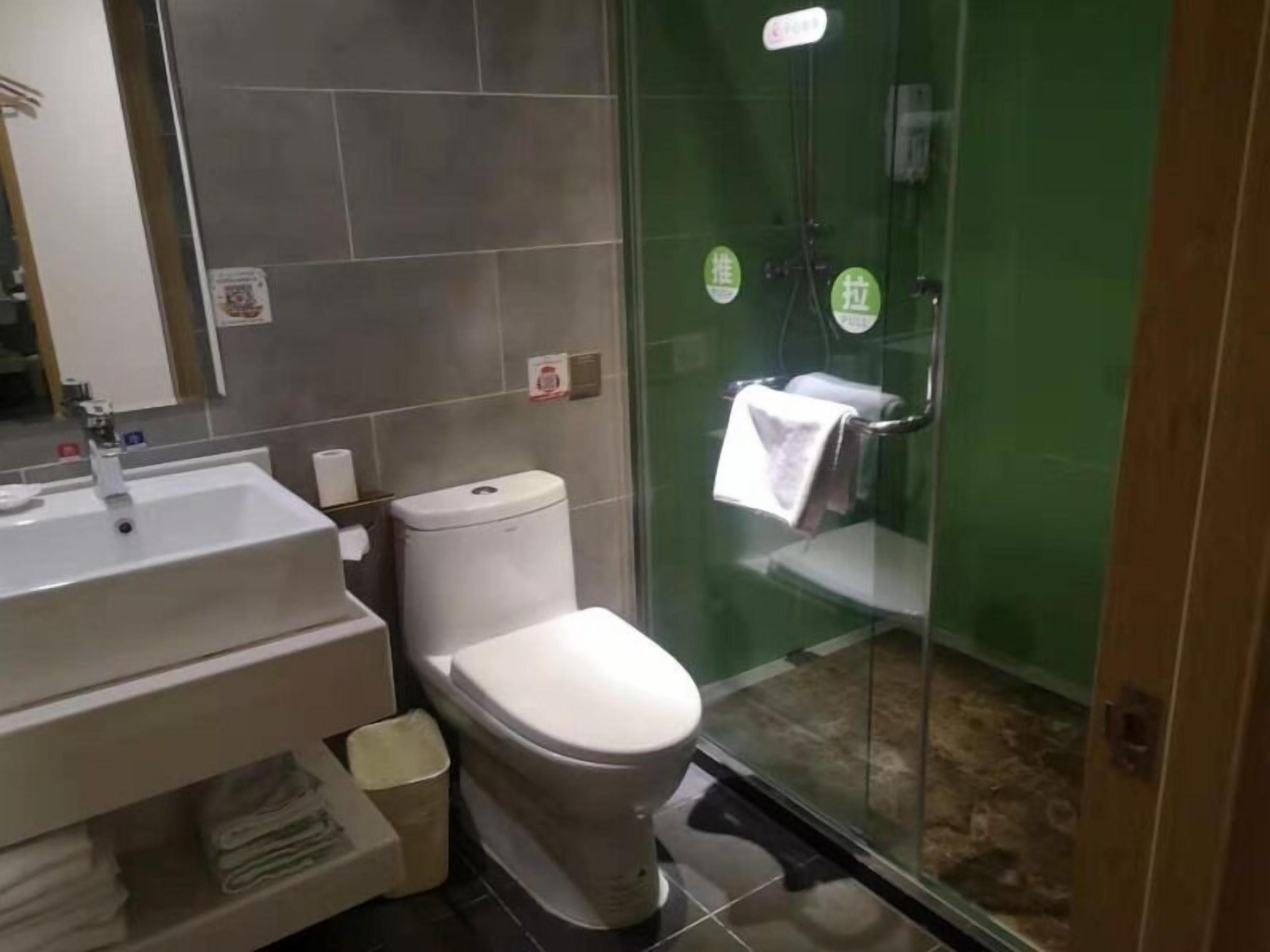 A modern bathroom with a white sink, toilet, and glass shower enclosure.