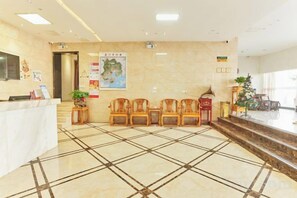A hotel reception area with a marble floor, reception desk, seating area, and a Christmas tree. - GreenTree Alliance Hotel (Xiamen Railway Station Sports Center) (Xiamen)