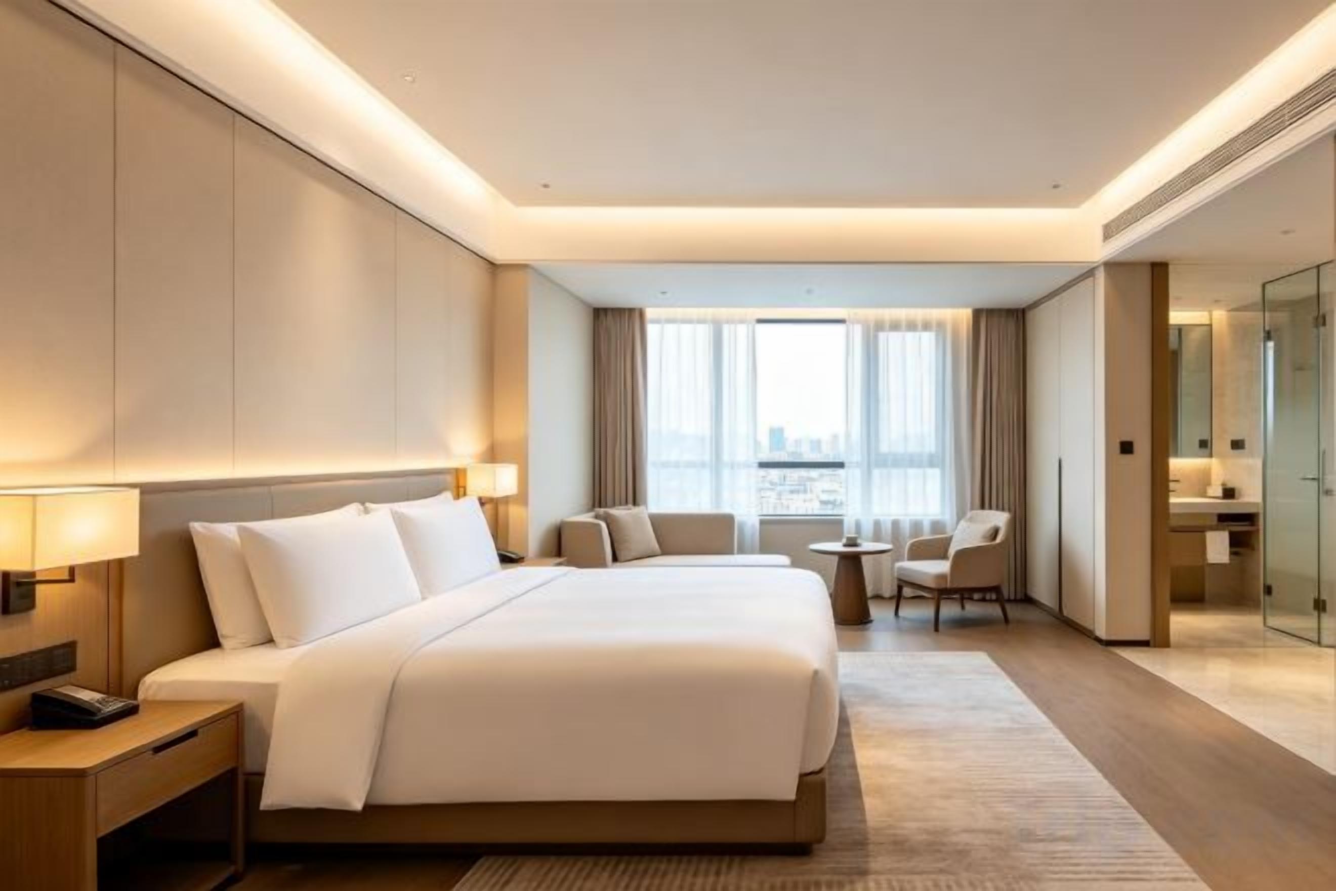 A hotel room with a large bed, bedside tables, a desk, and a view of the city.