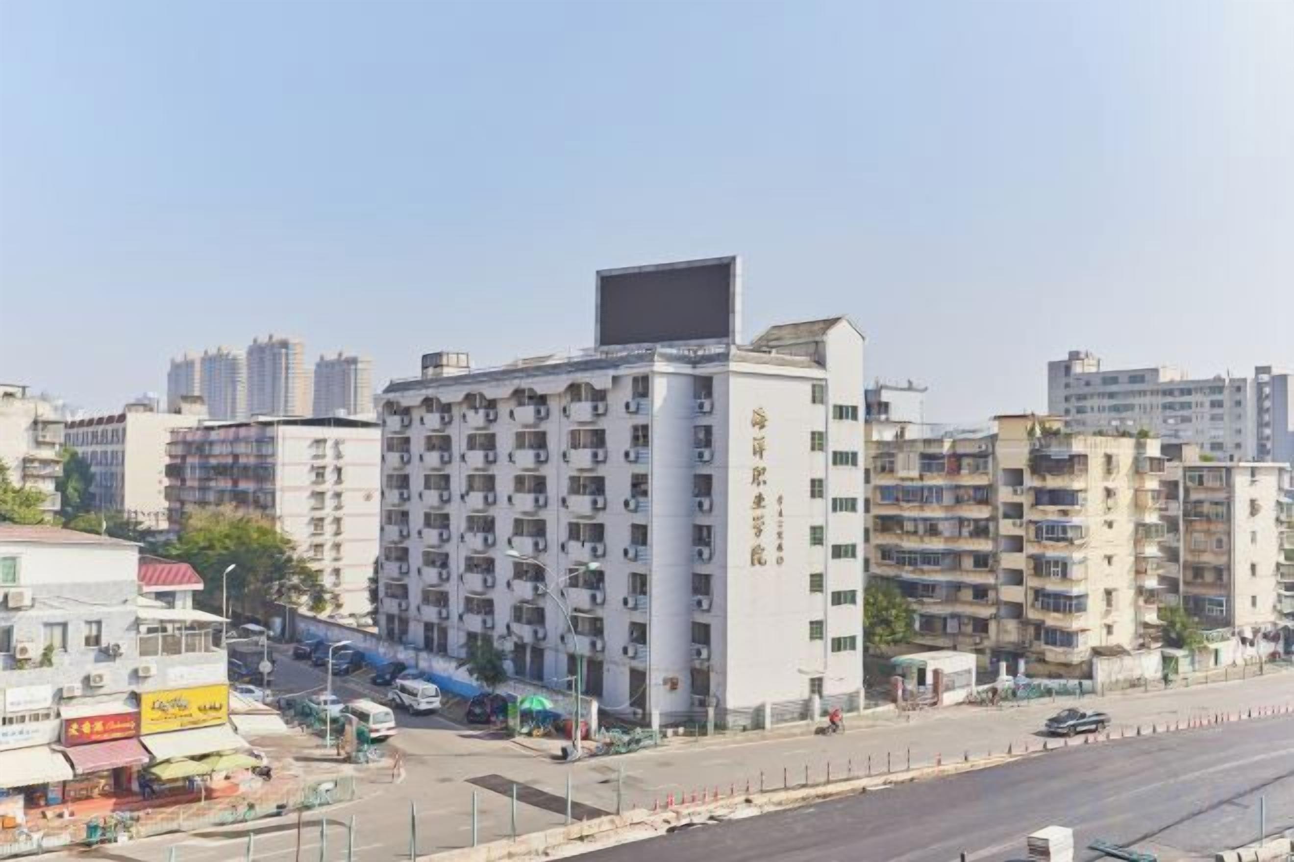 A multi-story hotel with a flat facade, located in an urban setting with other buildings in the background.