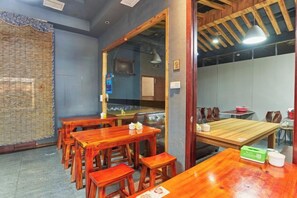 A restaurant interior with wooden tables and chairs, a counter, and a view through a glass door. - GreenTree Alliance Hotel (Xiamen Railway Station Sports Center) (Xiamen)
