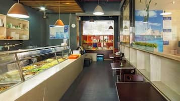 A restaurant interior with a buffet counter, seating area, and menu board.