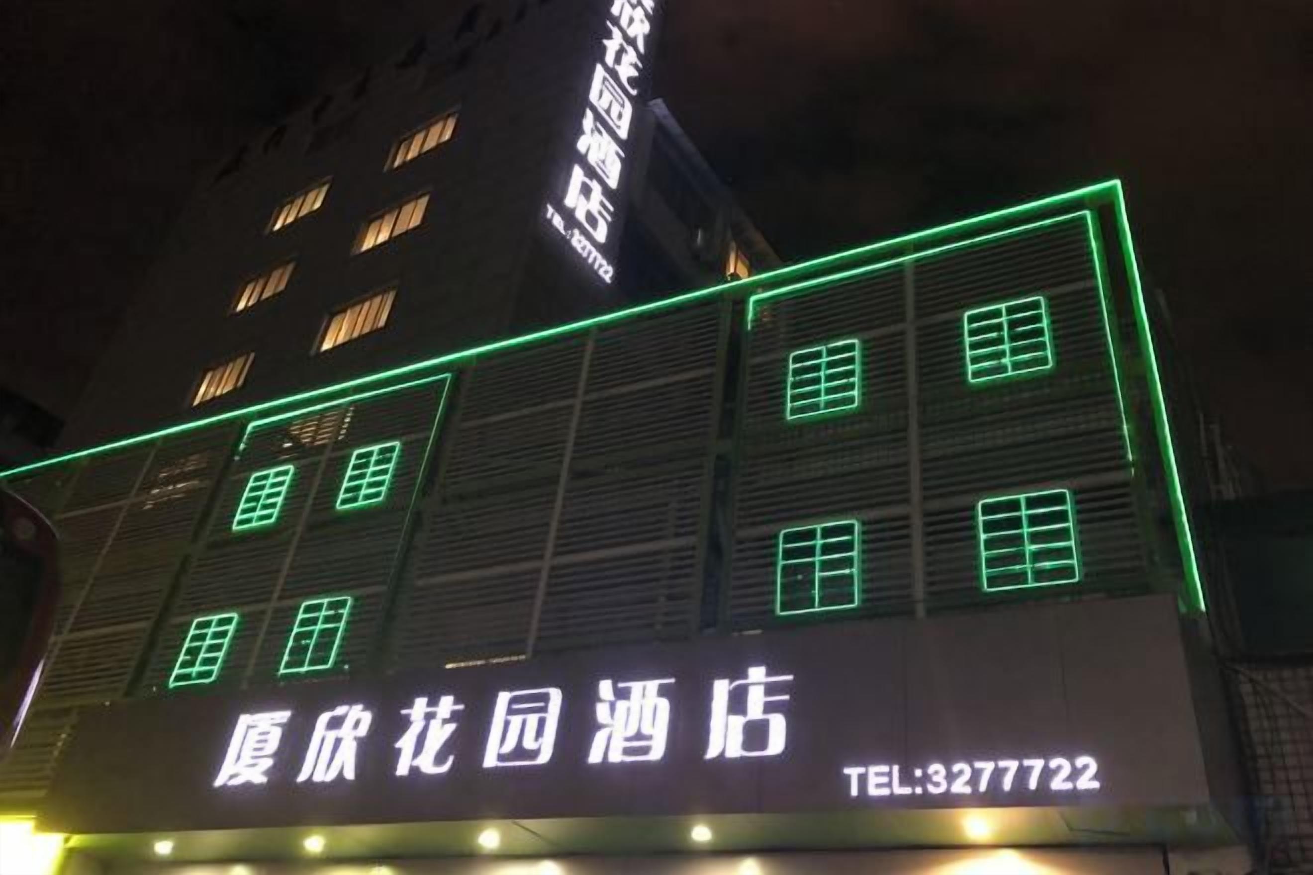 Un hotel con letreros iluminados y un número de teléfono visible.