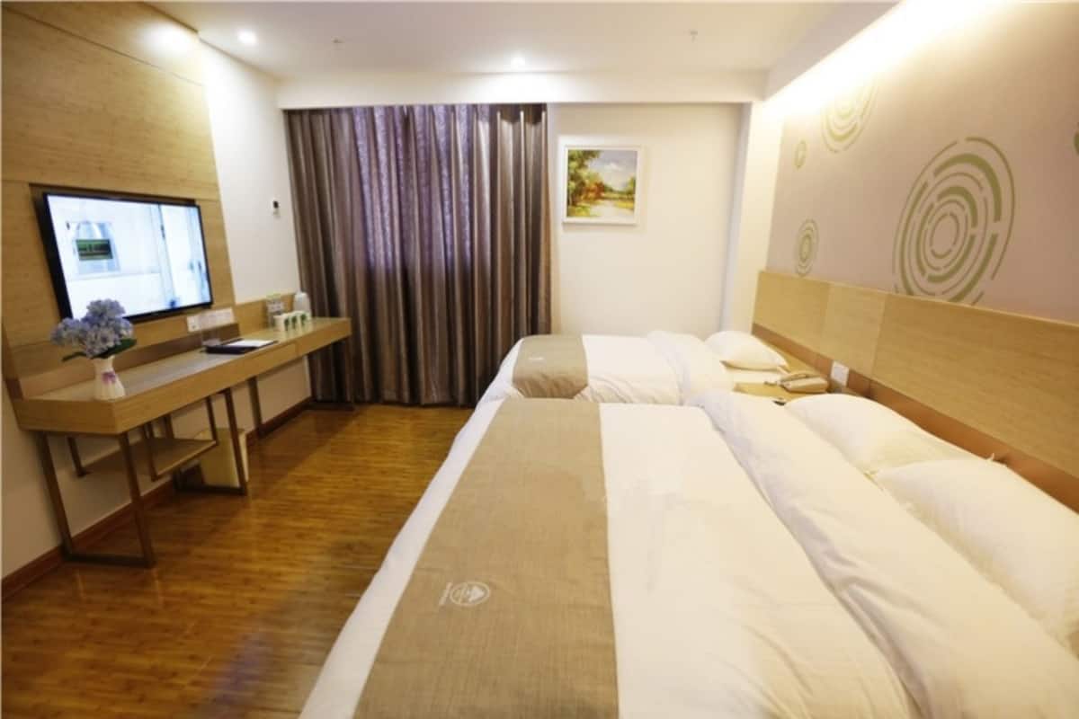Une chambre d’hôtel avec un lit, un bureau, une télévision et une fenêtre avec des rideaux.