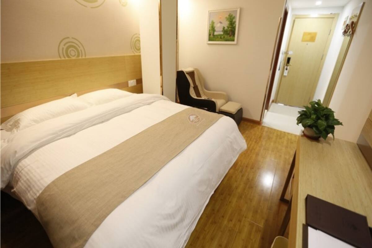 Une chambre d’hôtel avec un grand lit, une chaise, un bureau et une petite plante.