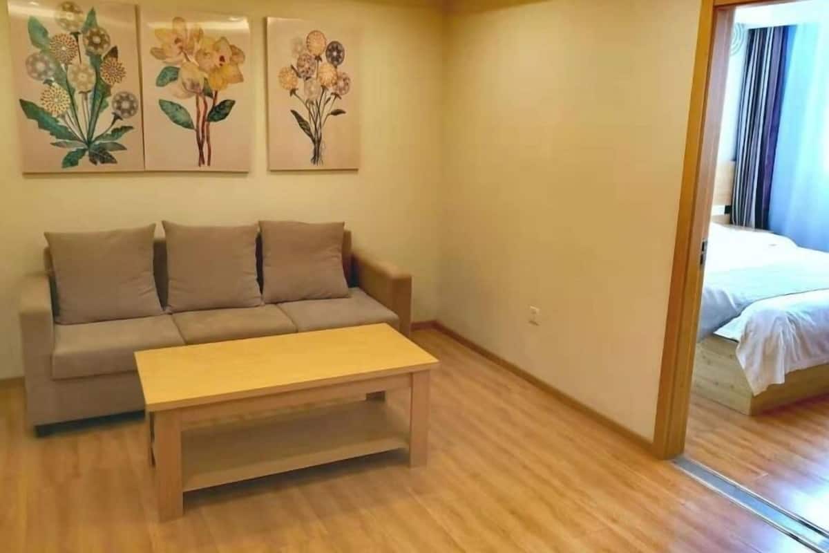Une pièce comprenant un canapé, une table basse en bois et trois tableaux aux motifs floraux accrochés au mur.