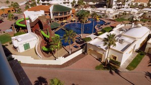 Ein Resort mit einem zentral gelegenen Pool, Liegebereichen und einer Rutsche.