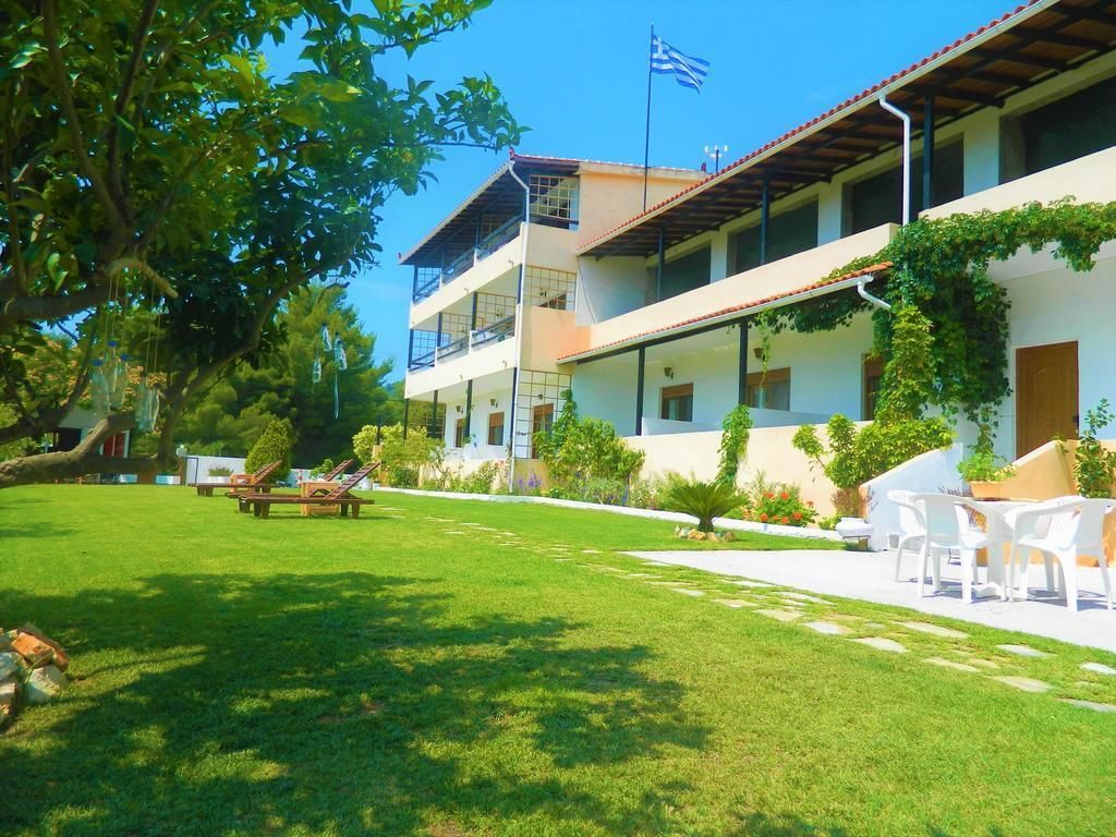 Un hotel de dos pisos, con mesas al aire libre y una bandera.