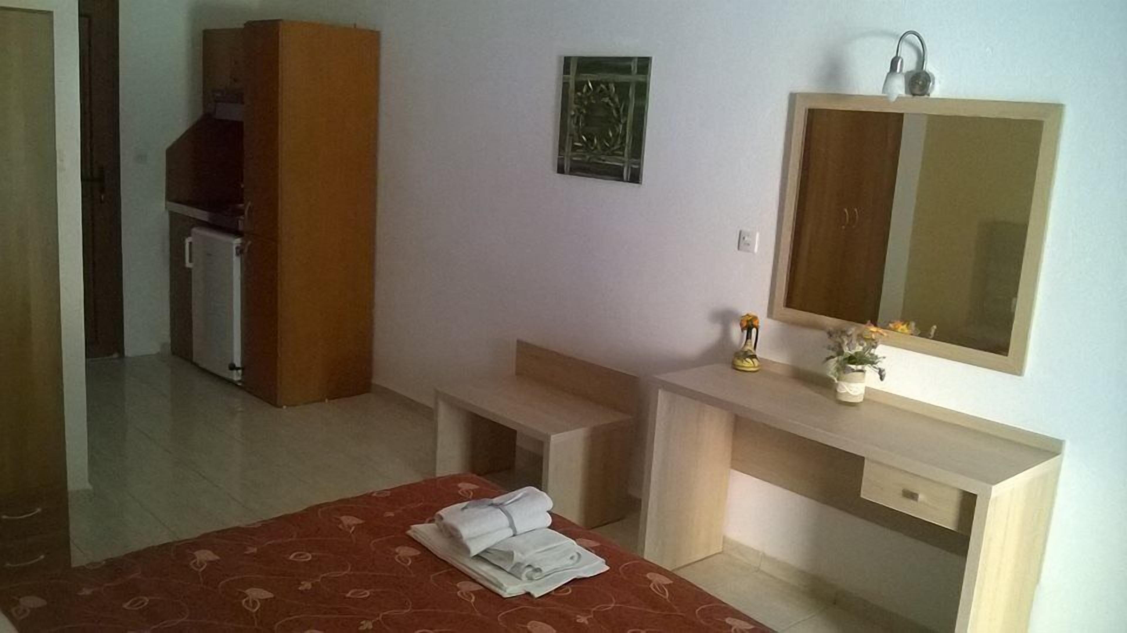 Una habitación de hotel con una cama, un escritorio, un espejo y un mueble bajo.