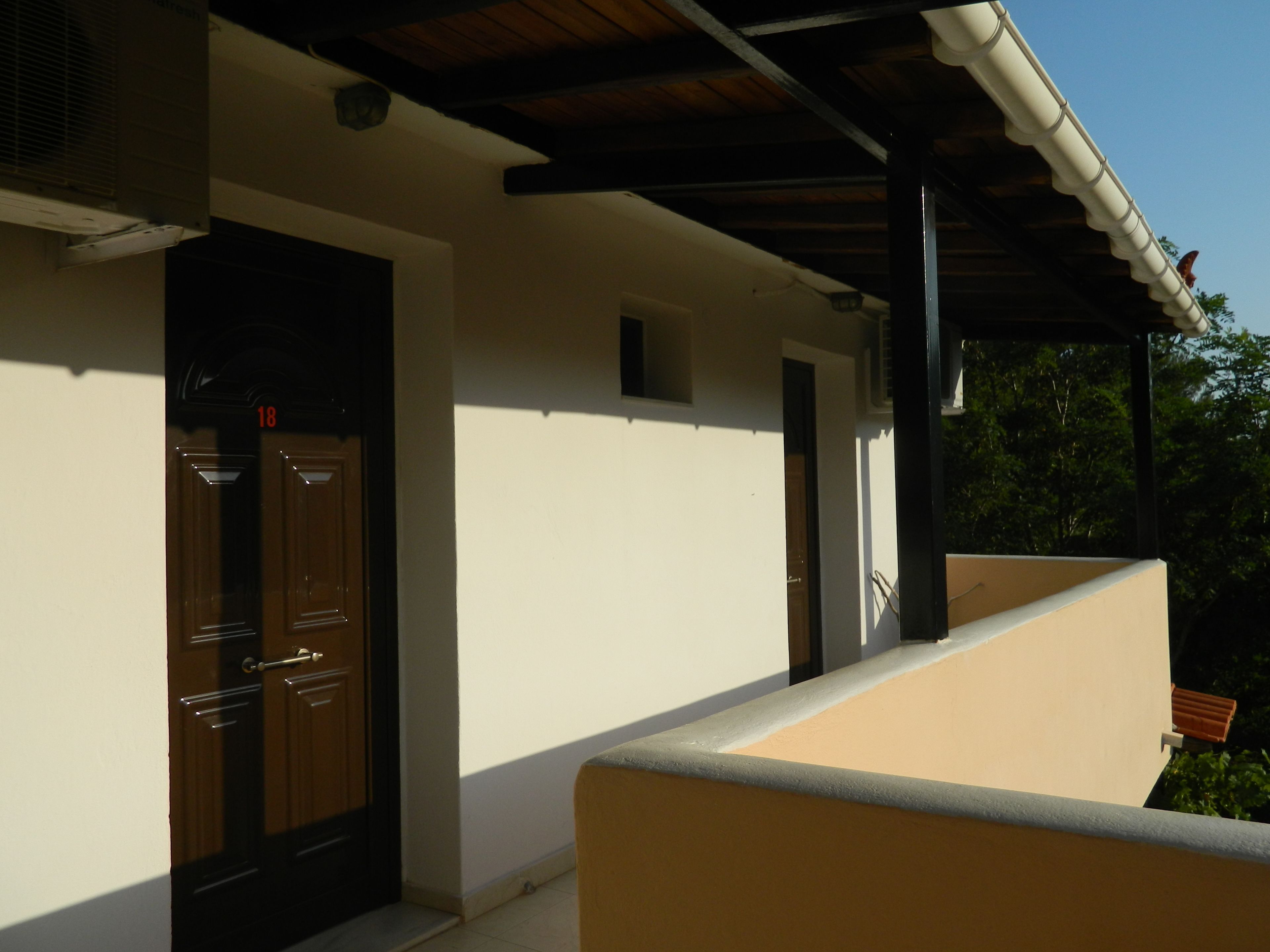 A building with a beige exterior, a dark brown door, and a small window above the door.